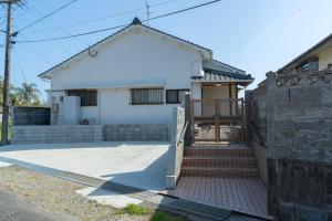 a white house with a gate and stairs in front at ひなたの宿結 in Miyazaki
