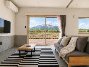 a living room with a couch and a large window at XYZ Niseko in Niseko