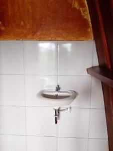a white sink in a white tiled bathroom at SKY SUNSET Bungalows in Tetebatu