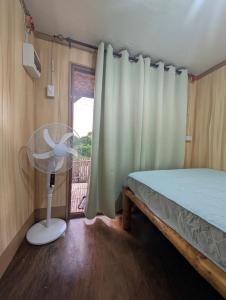a bedroom with a bed and a fan next to a window at Jadens Guesthouse in Siquijor +45 photos