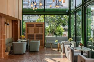 a restaurant with tables and chairs and windows at Happihaus Hotel Bangkok in Bangkok
