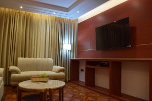 a living room with a couch and a tv on a wall at Hotel The Haven Kargil - Centrally Heated in Kargil