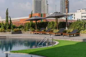 a pool with lounge chairs and umbrellas next to at Happihaus Hotel Bangkok in Bangkok