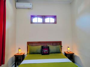a bedroom with a green bed with two night stands at Kaia Lovina Guest House in Lovina