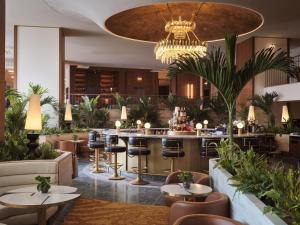 a restaurant with tables and chairs and a chandelier at Conrad Athens The Ilisian in Athens