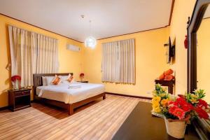 a bedroom with a bed and flowers in a room at Taratai Villa Guest House in Nong Prue +28 photos