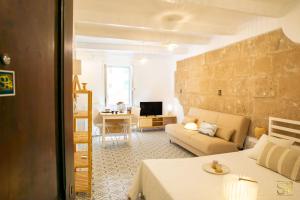 a bedroom with a bed and a living room with a couch at Petit Buragna in Alghero