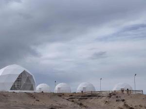 a group of domes on top of a dirt field at AK chatyr in Tong