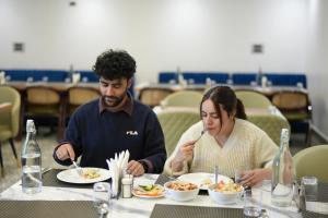 a man and woman sitting at a table eating food at Hotel The Haven Kargil - Centrally Heated in Kargil