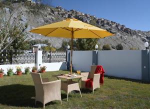 a table and chairs with a yellow umbrella at Hotel The Haven Kargil - Centrally Heated in Kargil