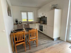 a kitchen with a table and two chairs and a kitchen with white cabinets at Bei Kleins in Nümbrecht