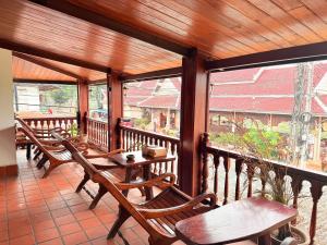 a porch with wooden tables and chairs and windows at Villa Ouis NamKhan River View in Luang Prabang
