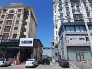 a street with cars parked in front of tall buildings at Beshic Hostel in Tashkent