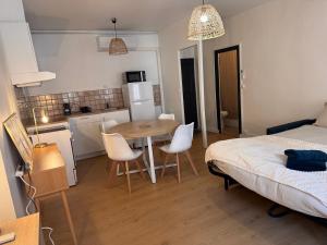 a room with a table and a bed and a kitchen at Studio climatisé in Narbonne