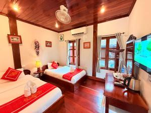 a room with two beds and a flat screen tv at Villa Ouis NamKhan River View in Luang Prabang