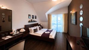 a bedroom with a bed and a desk and a mirror at Hotel Tihany Átrium in Tihany