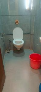 a small bathroom with a toilet and a red bucket at HOTEL Shiv Sai in Shirdi