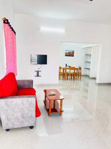 a living room with a red couch and a table at AAG Pride serviced apartments in Pollāchi