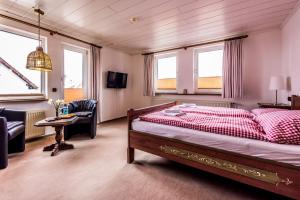 a bedroom with a bed and a couch and a table at Landhaus Brockenblick in Hohegeiß