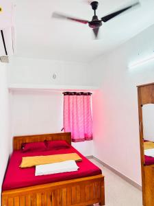 a bedroom with a bed with red sheets and a ceiling fan at AAG Pride serviced apartments in Pollāchi
