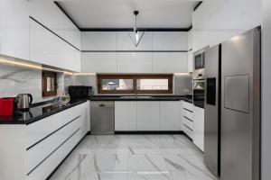 a white kitchen with white cabinets and appliances at Oasis Luxury Villa in Rhodes Town