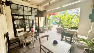 a restaurant with tables and chairs in a room with plants at Anders Arjuna Selatan in Jakarta