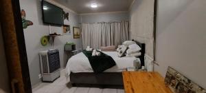 a bedroom with a bed with white sheets and a television at Malan's Siësta 2 in Kimberley