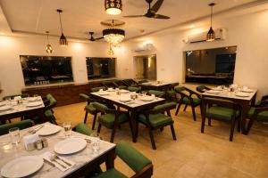 a dining room with tables and green chairs at Aqua Tree Resort in Rishīkesh