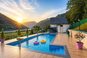 a swimming pool with a sunset in the background at Aqua Tree Resort in Rishīkesh