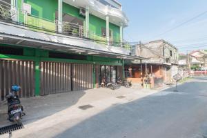 a green building with motorcycles parked next to a street at RedDoorz Plus near Siloam Hospital Balikpapan in Balikpapan