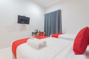 a hotel room with two beds and a tv at RedDoorz Plus near Siloam Hospital Balikpapan in Balikpapan
