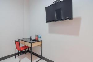a desk with a chair and a television on a wall at RedDoorz Plus near Siloam Hospital Balikpapan in Balikpapan +22 photos