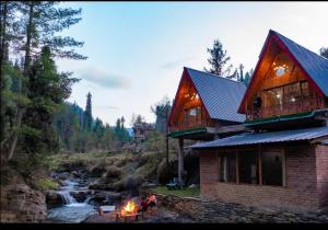 a group of people sitting around a fire in front of a house at The Riverbank Nest in Jibhi