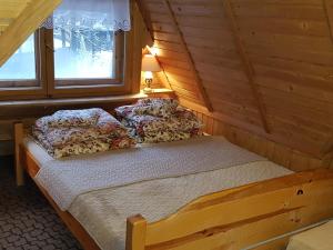 uma cama num chalé de madeira com duas janelas em Domek Drewniany Tetmajera Centrum Zakopane em Zakopane