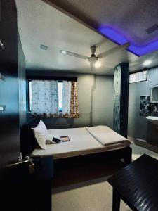 a bed in a room with a purple light at Hotel MK in Ratlām
