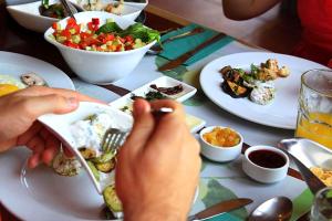 a table with plates of food and a person holding a fork at דונה דינה Donna Dina in Amirim