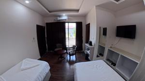 a room with two beds and a desk and a television at The View Hotel Falkland in Āīzawl