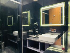 a black bathroom with a sink and a mirror at City Center Suites in Bhatinda +32 photos