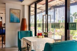 a dining room with a table and chairs and windows at Jomtien Beach Sleep Inn - Steps from Beach & Market in Jomtien Beach