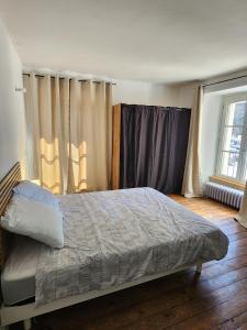 a bedroom with a bed and a window with curtains at Joli appartement T3 in Allassac