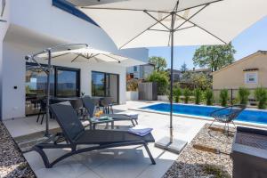 a patio with a chair and umbrella next to a swimming pool at Villa Vela in Brzac