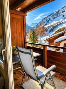 a chair on a balcony with a view of a mountain at Chalet Höfi - Ski-in Ski out at Hörnlilift by Arosa Stay in Arosa +1 photo