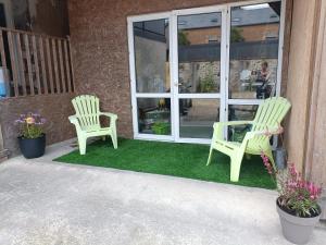 two green chairs sitting on a porch with grass at Les caves Sainte Anne Ecommoy 72220 in Écommoy