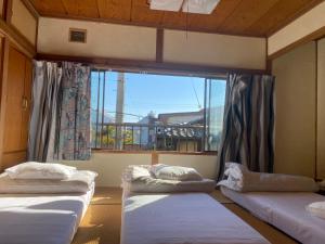 three beds in a room with a large window at Guesthouse Azumaya 2nd in Matsumoto +10 photos