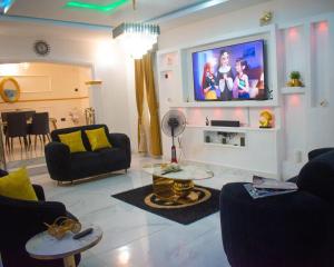 a living room with a couch and a tv on a wall at Isuki apartment in Benin City