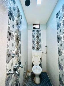 a bathroom with a toilet and flowers on the wall at Hotel MK in Ratlām
