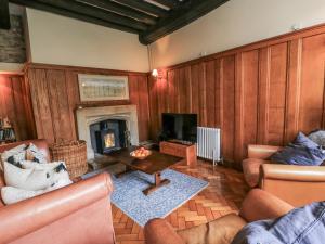 a living room with wooden walls and a fireplace at Ostlers in Burford