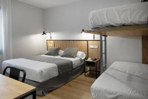 ein Schlafzimmer mit zwei Etagenbetten, einem Tisch und einem Schreibtisch in der Unterkunft Hotel Marfany in Andorra la Vella