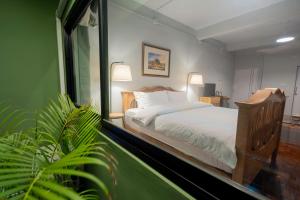 a bedroom with a bed and a large window at Baan Batra Heritage Suite in Bangkok