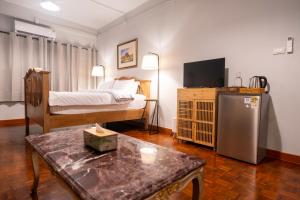 a room with a bed and a television and a table at Baan Batra Heritage Suite in Bangkok